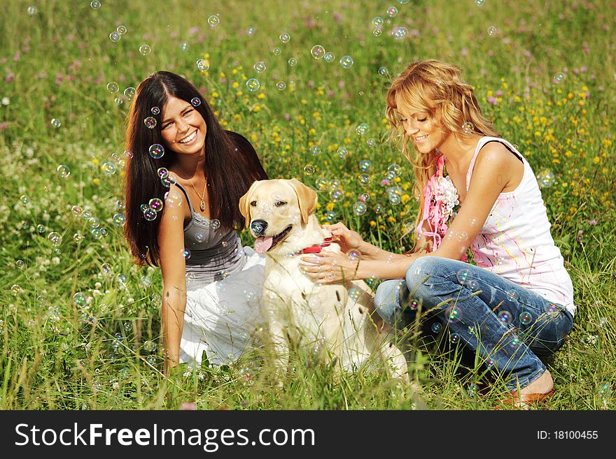 Girlfriends and dog in green grass field
