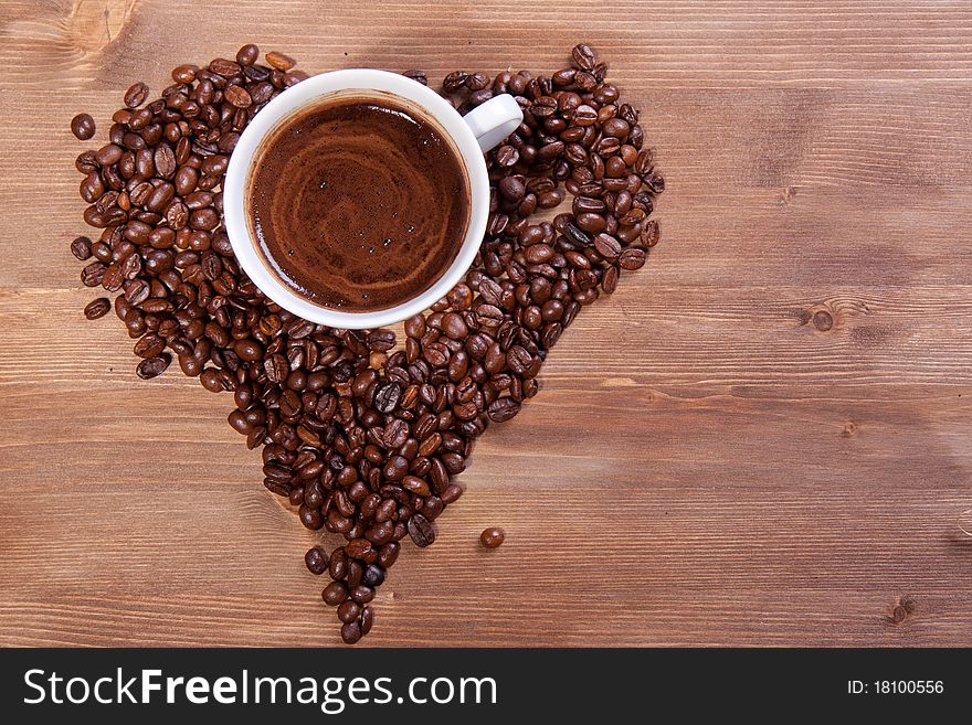 White cup of black coffee with coffee beans as a heart