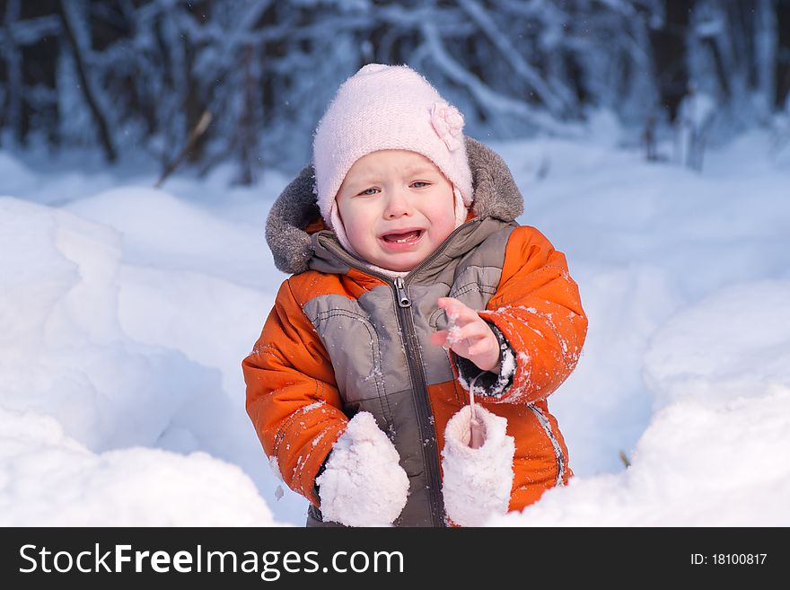 Adorable baby disappointed after eat cold snow in winter forest. Take away one mitten