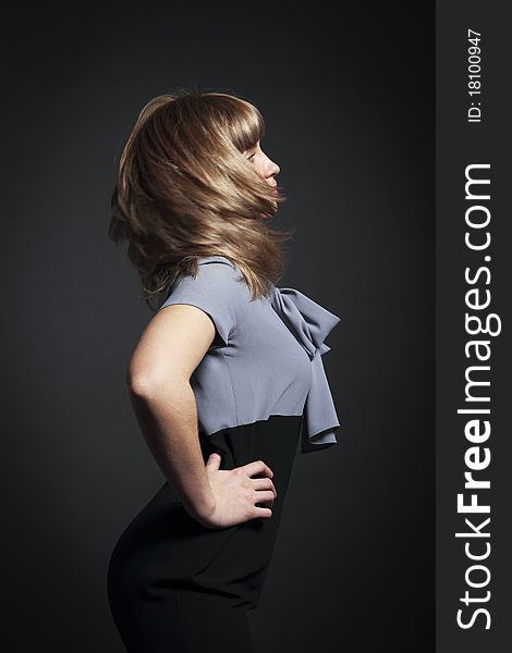 Portrait of young beauty woman with fluttering hair over dark background