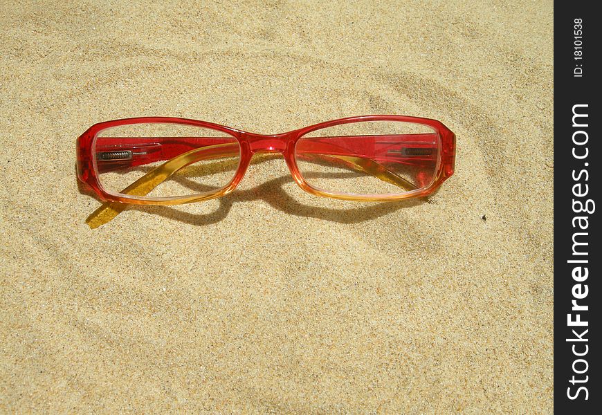 Red eyeglasses in the sand.