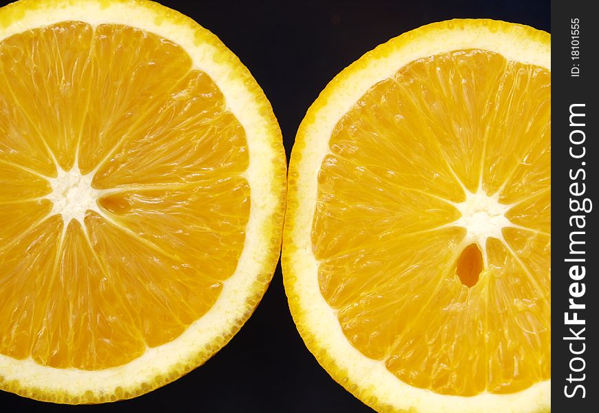 Two orange slices on a dark background. Two orange slices on a dark background