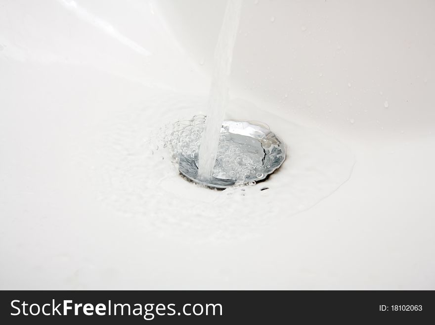 Closeup photo if Washbasin and running water. Closeup photo if Washbasin and running water