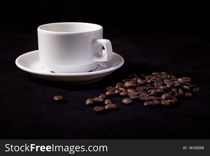 Coffee cup and spilled coffee beans on black. Coffee cup and spilled coffee beans on black