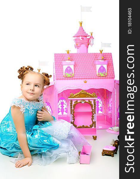 Beautiful little girl in princess dress playing with her toy castle. Isolated over white background.