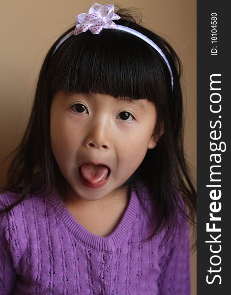 Cute young Asian girl pulling funny face with tongue out, studio background. Cute young Asian girl pulling funny face with tongue out, studio background.