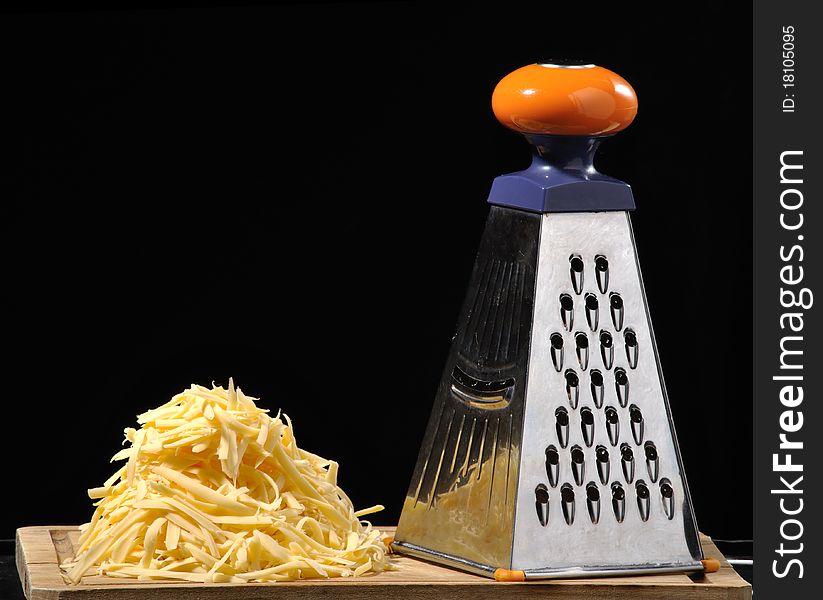 Still life with grated cheese and the grate against black background