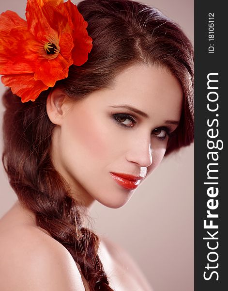 Portrait of a beautiful woman with a braid and flower on natural background