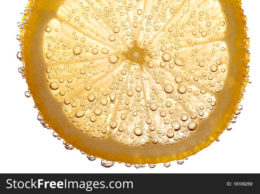 Partially transparent lemon slice floating in effervescent liquid