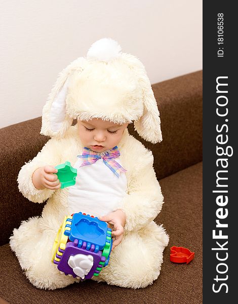 Pretty caucasian baby in rabbit costume playing with toy