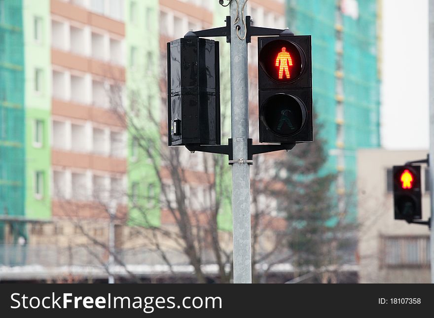 Red pedestrian traffic light with buildings on background