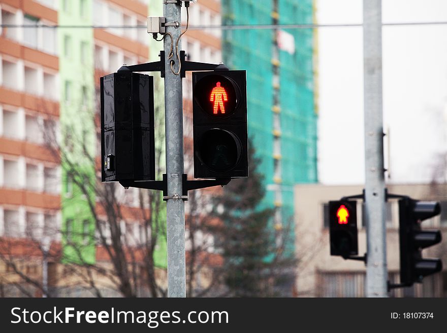 Red pedestrian traffic light with buildings on background