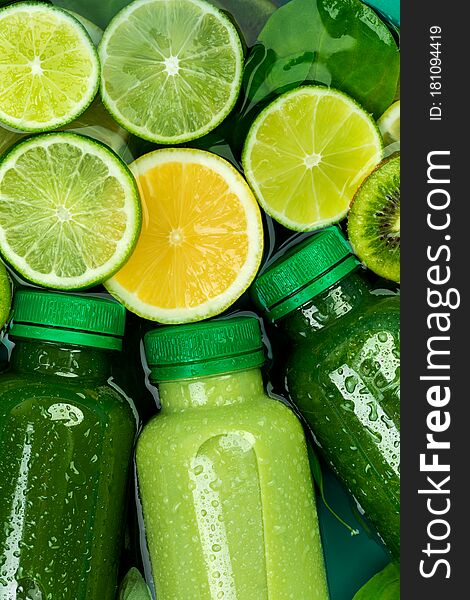 Close-up of fresh chilled green detox-smoothies surrounded by slices of lemon, lime, kiwi and spinach leaves. diet concept, good nutrition, citrus, vegetarian background. Close-up of fresh chilled green detox-smoothies surrounded by slices of lemon, lime, kiwi and spinach leaves. diet concept, good nutrition, citrus, vegetarian background