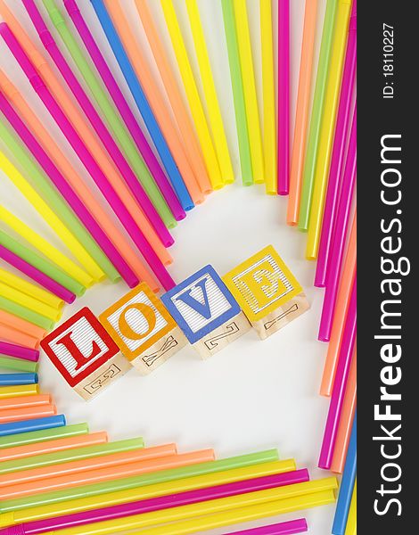 Colorful Straws make a heart shape and childrens bloks spell the word Love. Colorful Straws make a heart shape and childrens bloks spell the word Love.