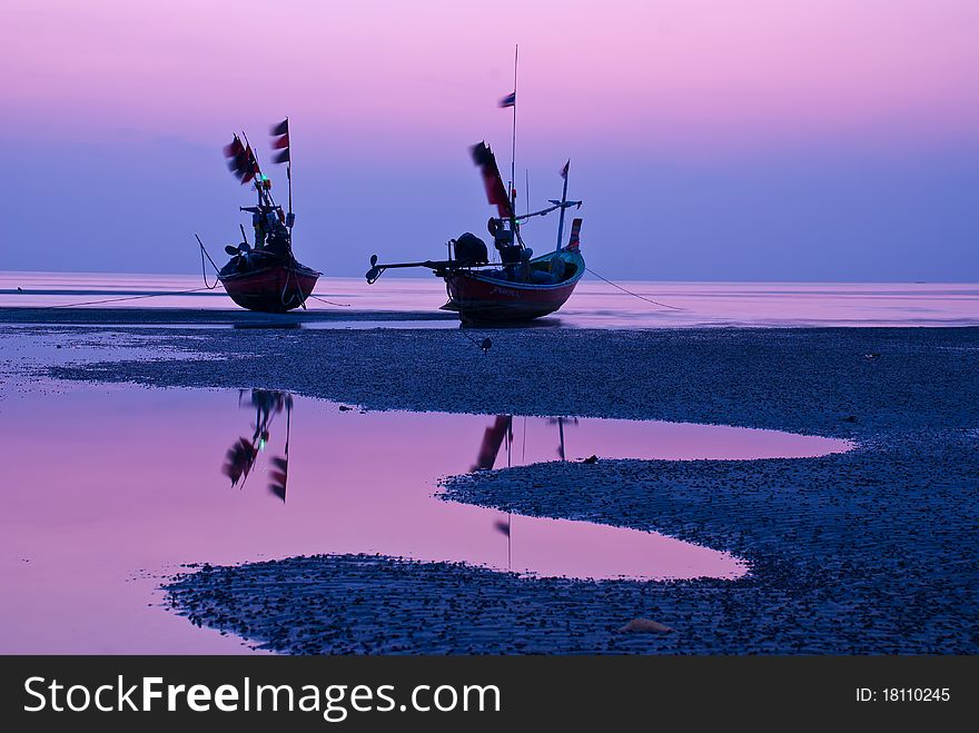 Landscape of beach and two boats at twilight .