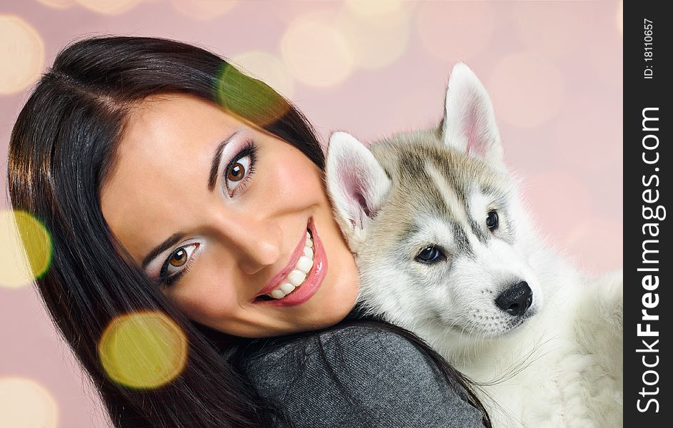 Playing woman with puppy of siberian haski on pink background with confetti. Playing woman with puppy of siberian haski on pink background with confetti