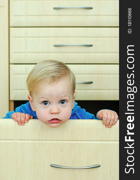 White haired little boy in the kitchen cabinet