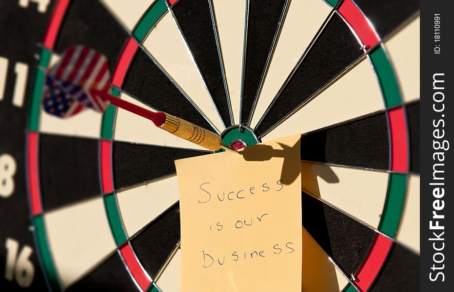 Dartboard with the arrow in center and a note creating a business concept. Dartboard with the arrow in center and a note creating a business concept.