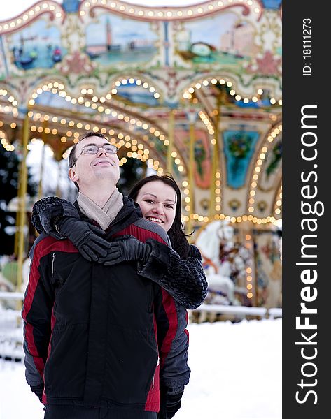 Happy couple looking at carousel in winter time