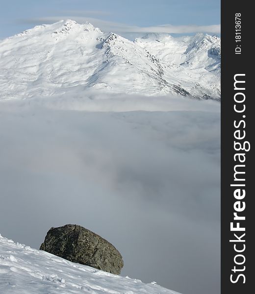 Stone on snow and inversion in mountains in winter, France, Savoy Alps. Stone on snow and inversion in mountains in winter, France, Savoy Alps