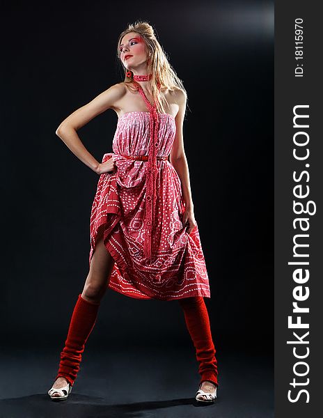 Extravagant fashion model in red clothing against black background
