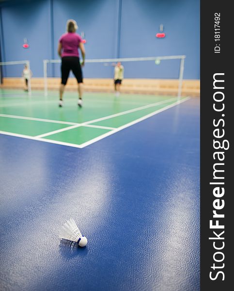 Badminton - badminton courts with players competing; shuttlecocks in the foreground (shallow DOF; color toned image)