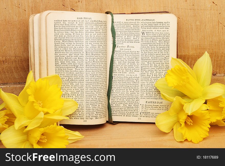 Antique prayer book open on Easter prayers surrounded by daffodil flowers against an old wooden panel. Antique prayer book open on Easter prayers surrounded by daffodil flowers against an old wooden panel