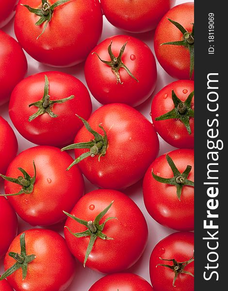 Many red-ripe tomatoes close on a light background