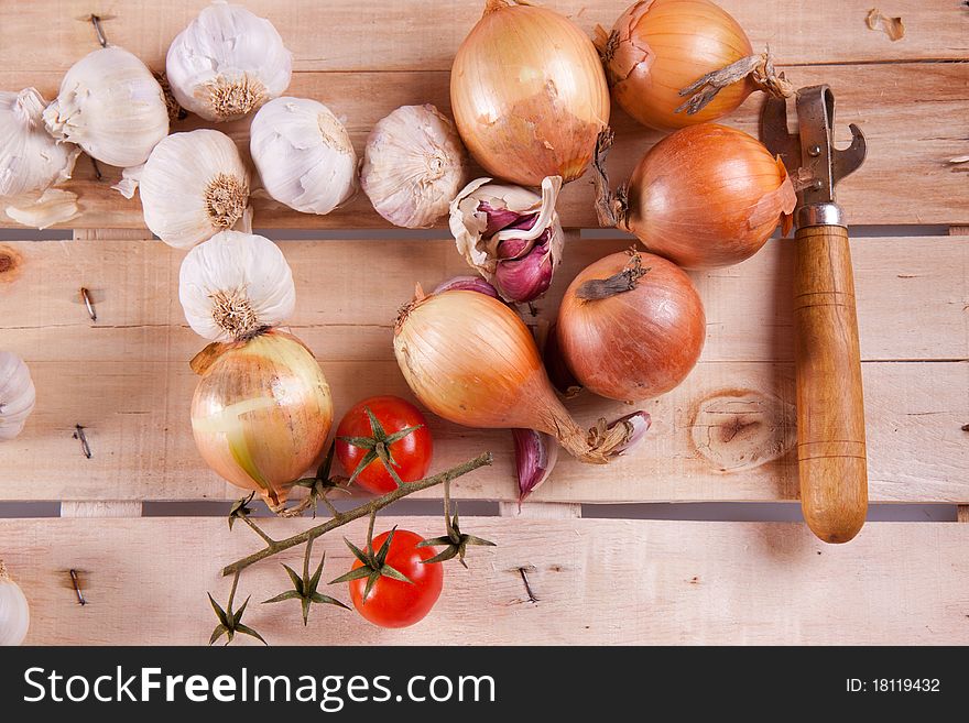 Onion, garlic and tomato on a wooden desk in sun shine
