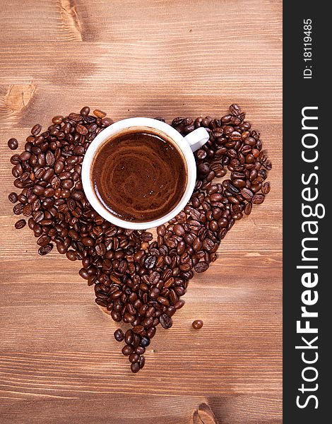 White cup of black coffee with coffee beans as a heart