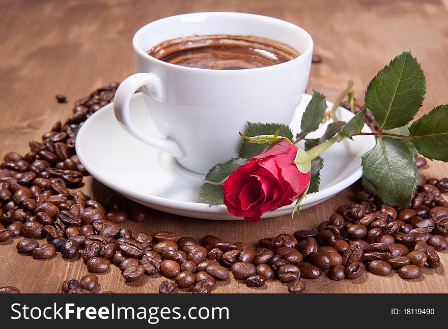 White cup of black coffee with coffee beans and red rose