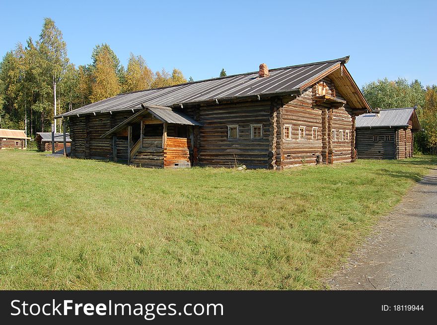 The wooden house in village and green vegetation, on a background is visible wood.