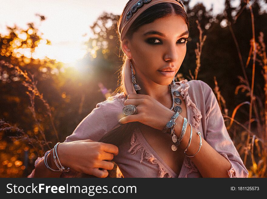 Beautiful young fashionable woman in dress on the field at sunset