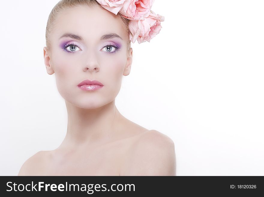 Portrait of young beautiful woman with roses in hair, on white background