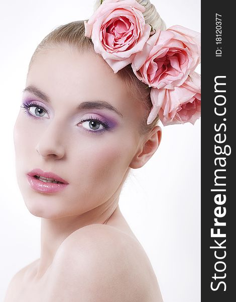 Portrait of young beautiful woman with roses in hair, on white background