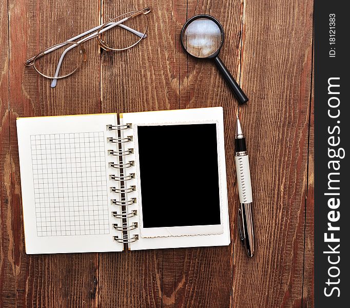 Note with old photo, pen, magnifying glass and eyeglasses on wood background. Note with old photo, pen, magnifying glass and eyeglasses on wood background