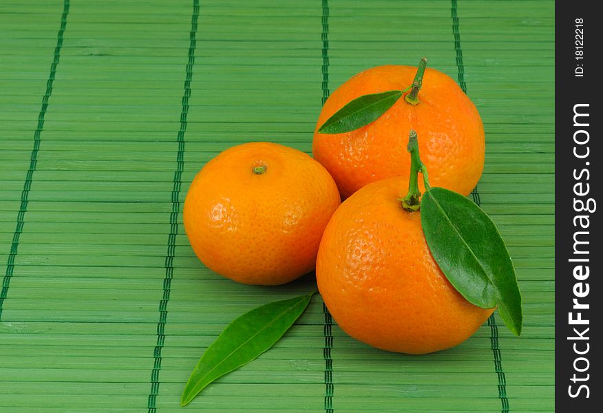 Several mandarins and leaves on green background. Several mandarins and leaves on green background