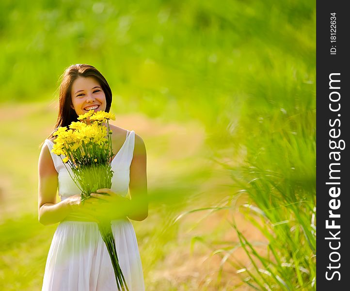 Adorable girl with flowers poses in a field during summer afternoon. Adorable girl with flowers poses in a field during summer afternoon.