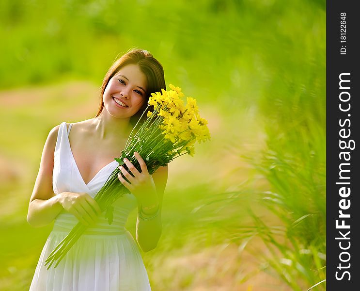 Adorable girl with flowers poses in a field during summer afternoon. Adorable girl with flowers poses in a field during summer afternoon.