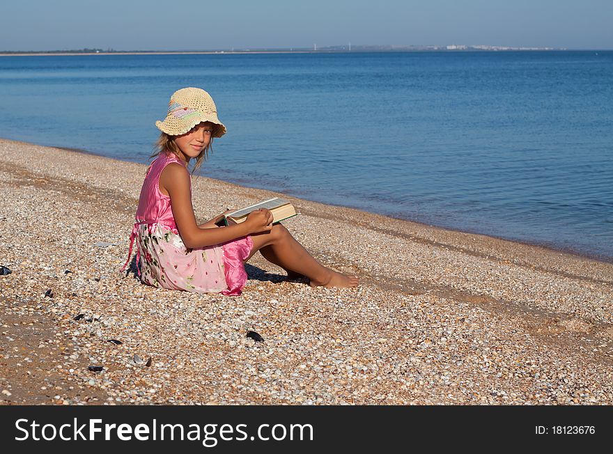 Girl child reads a book at the beach. Girl child reads a book at the beach
