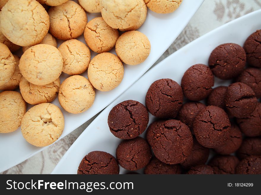 Black and vanilla home made cookies on plates over a damask tablecloth. Black and vanilla home made cookies on plates over a damask tablecloth