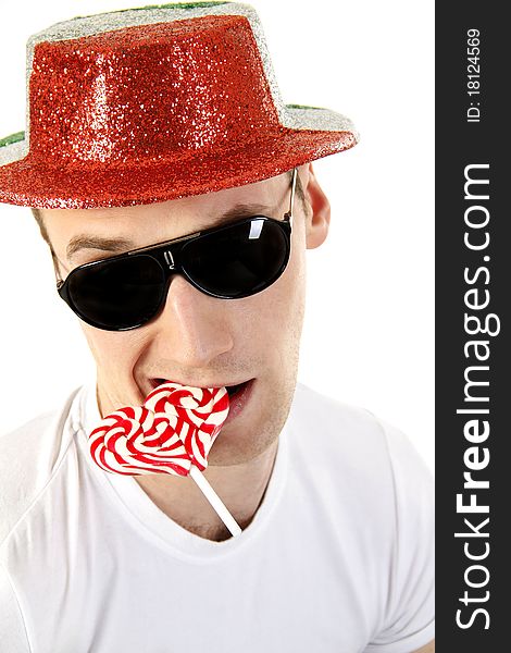 Young man in sun glasses with a candy in the shape of a heart on the white background