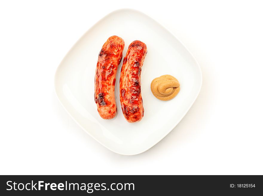 Appetizing grilled sausages with mustard on a plate.