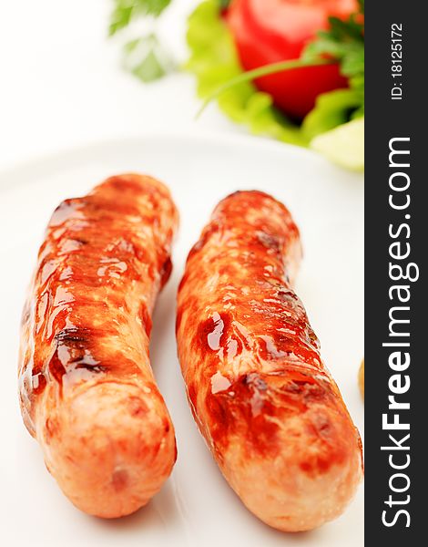 Appetizing grilled sausages with vegetables on a plate. Appetizing grilled sausages with vegetables on a plate.