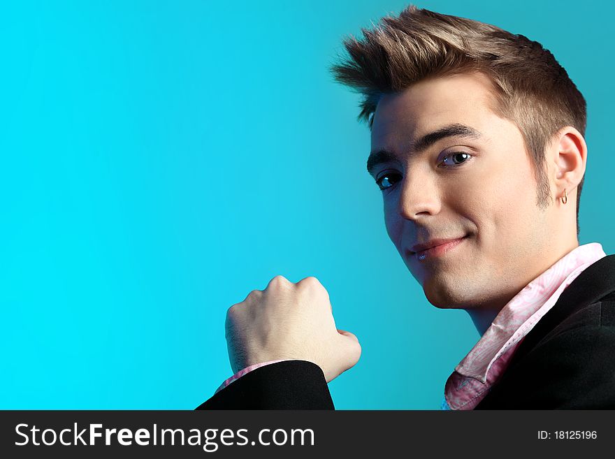 Young man dressed in rock'n'roll style, posing over blue background. Young man dressed in rock'n'roll style, posing over blue background.