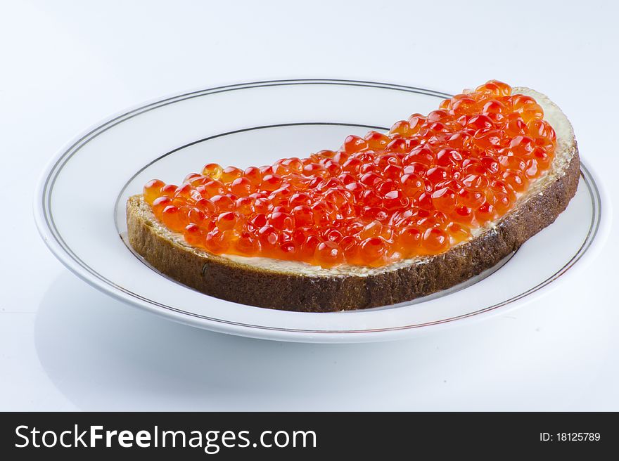 Red caviar sandwich with a brow bread on the plate over the light background