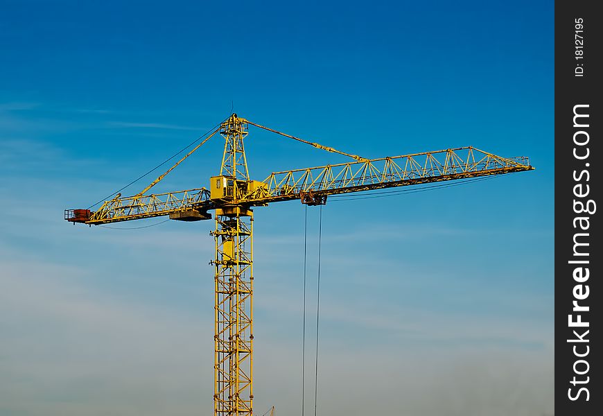 High building crane against the blue sky background. High building crane against the blue sky background
