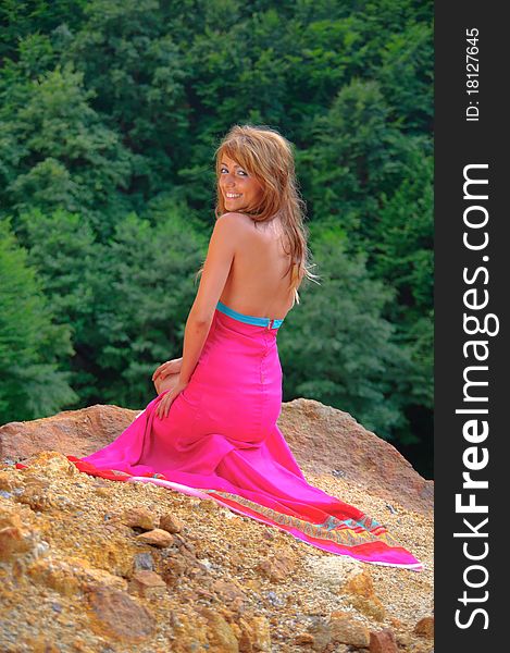 young girl smiling dressed in pink dress and standing on a rock. young girl smiling dressed in pink dress and standing on a rock.