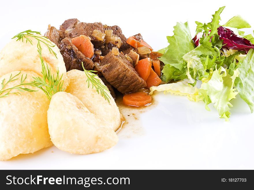 Meal of stewed beef steak with roast potatoes and fresh salad. Meal of stewed beef steak with roast potatoes and fresh salad