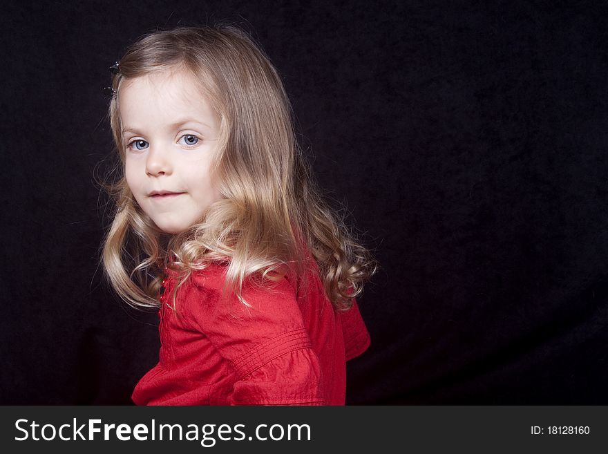 A little girl in red dress looking at camera with small smile. A little girl in red dress looking at camera with small smile